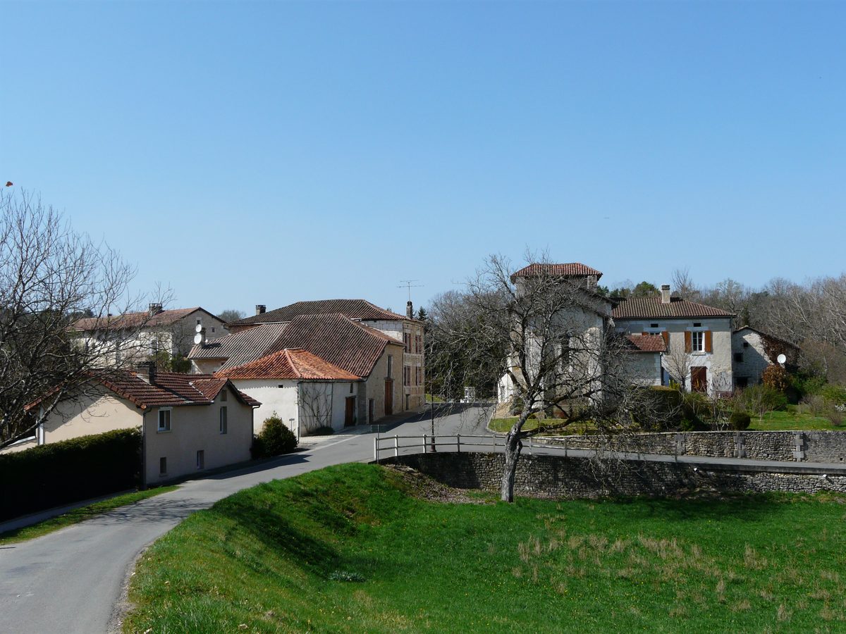 Vue du bourg de Saint-Pancrace : maisons de pierre et toits de tuiles le long de la route, sous un ciel d’azur